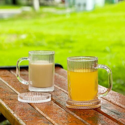 Two glass mugs with beverages on a wooden table outdoors.