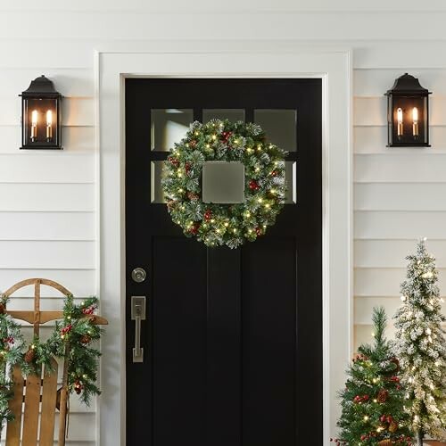 Festive holiday wreath on black front door with lanterns.