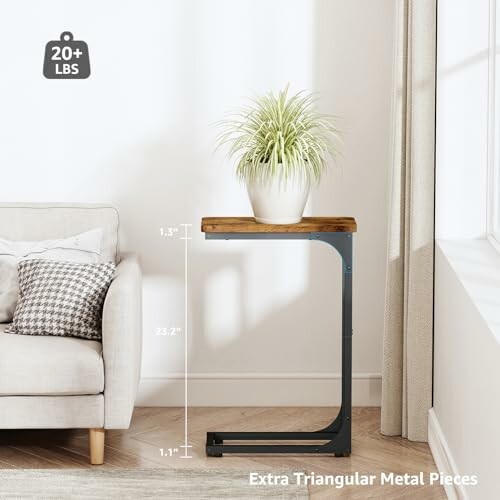 Modern side table next to a sofa with a plant on top.