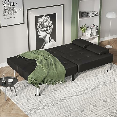 Modern black sofa bed with green throw in stylish living room.