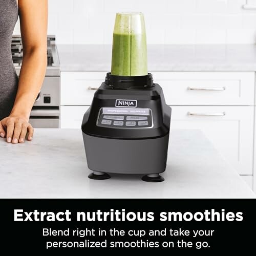 Ninja blender with green smoothie in a kitchen setting.