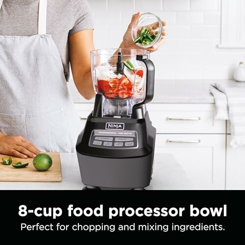 Person using Ninja food processor with vegetables.